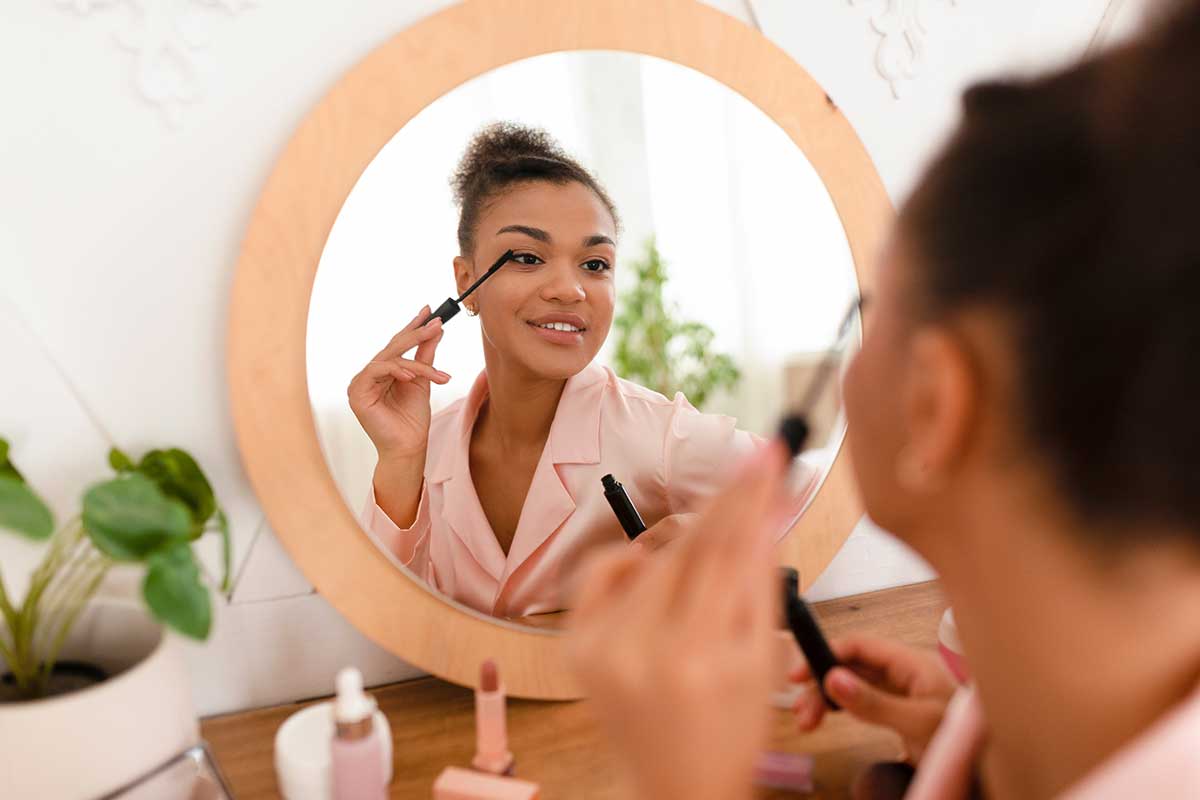 cosmetics-industry applying makeup while looking in mirror